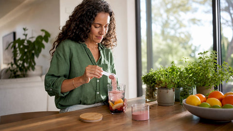 Woman preparing fiber supplement drink at home kitchen table