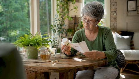 Senior woman reviewing eye health supplements at table